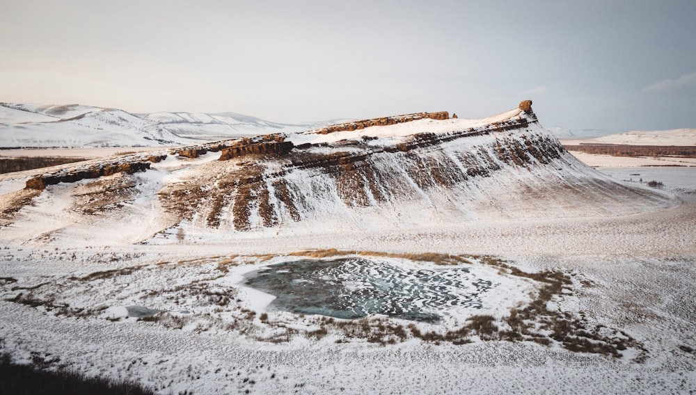 a snow covered mountain with a pool of water