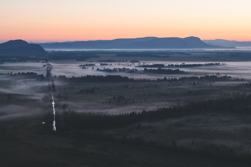 a foggy valley with mountains in the distance