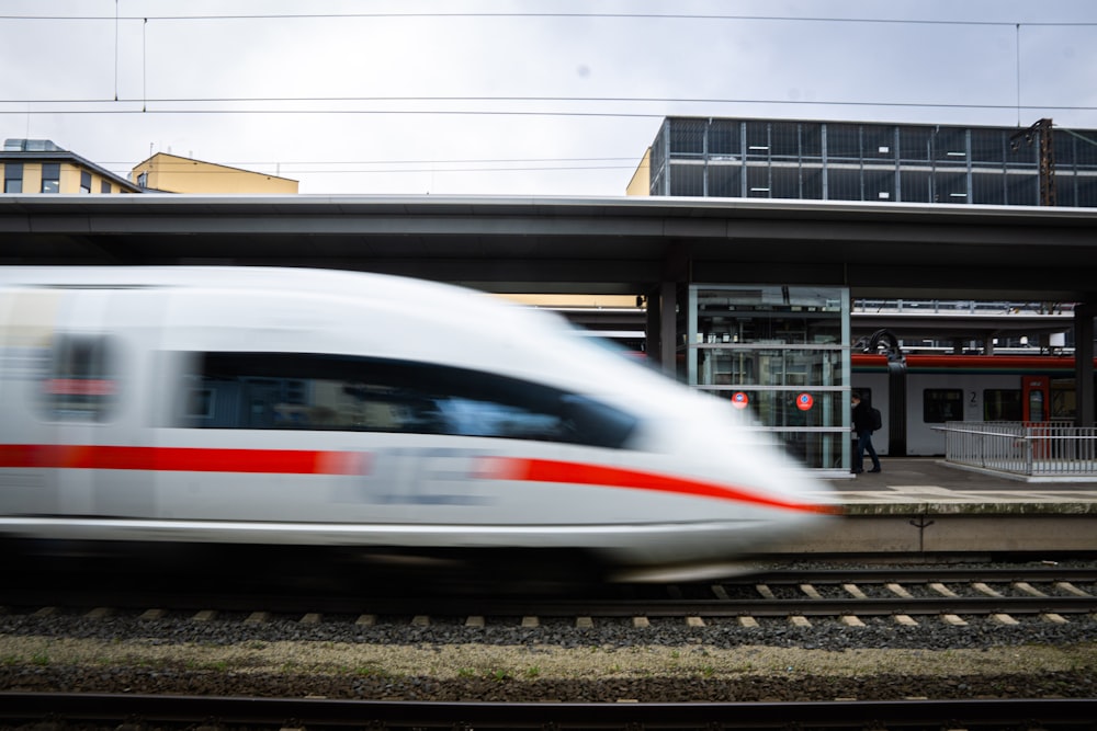 a white and red train traveling past a train station