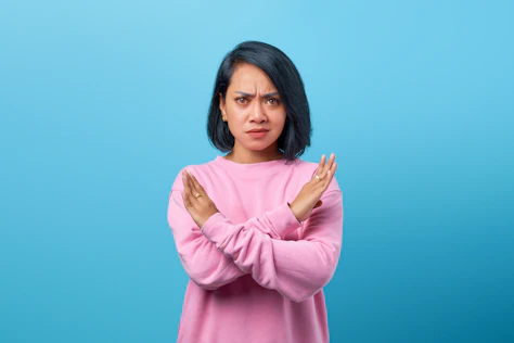 a woman in a pink sweater is holding her hands together