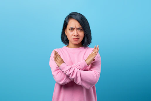 a woman in a pink sweater is holding her hands together
