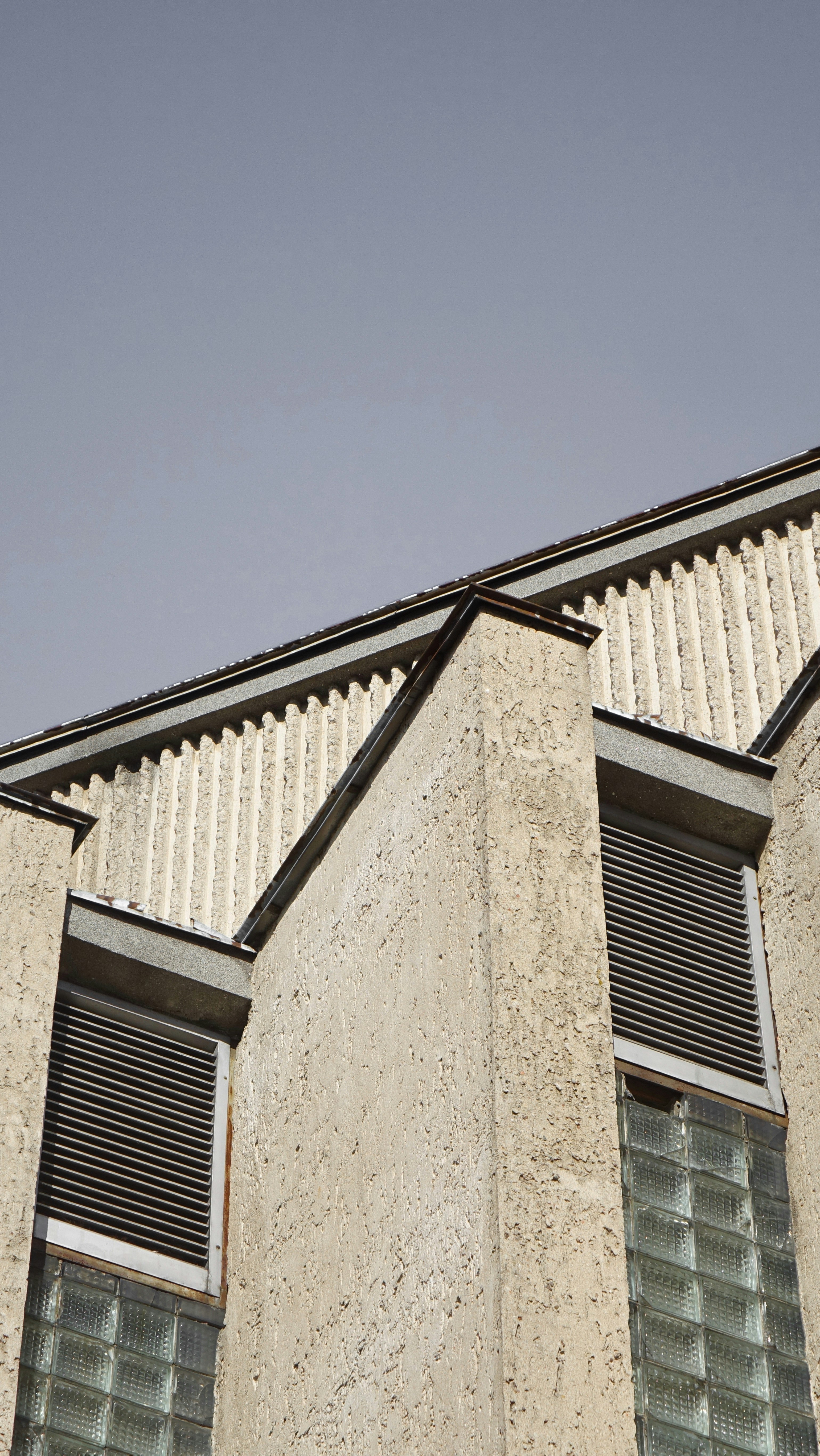 a tall building with two windows and a sky background