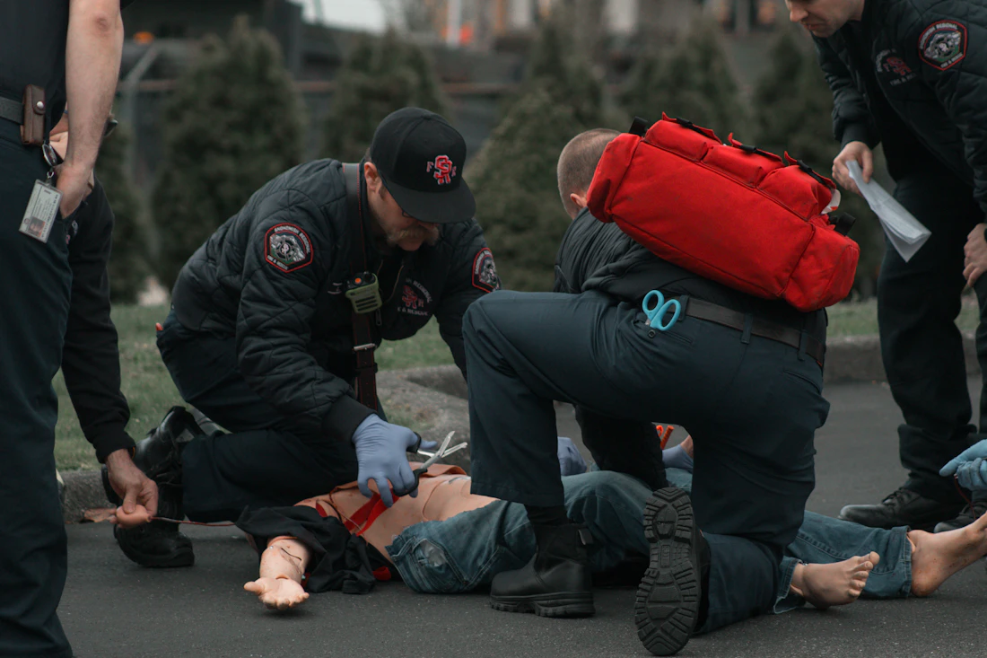Paramédicos uniformados atendiendo a una persona en el suelo durante una práctica de emergencia