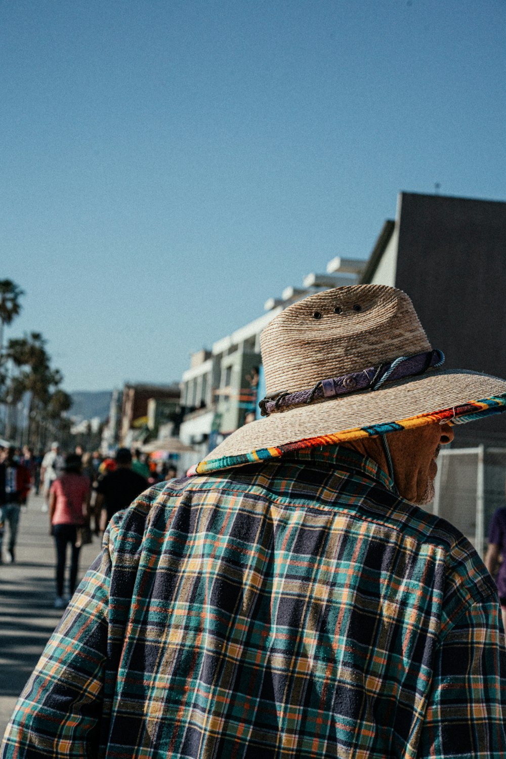 a man wearing a hat walking down a street
