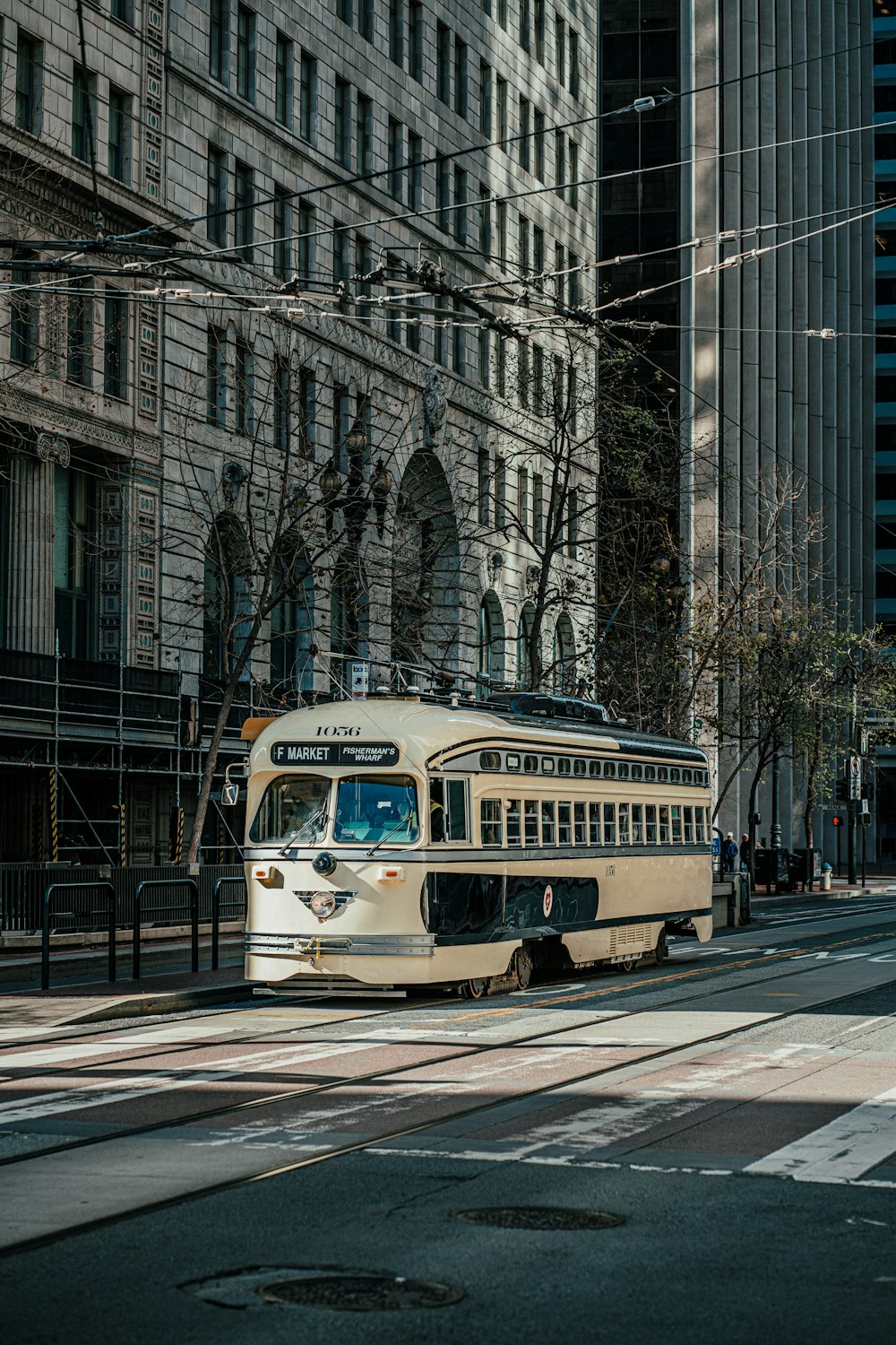 a white bus driving down a street next to tall buildings