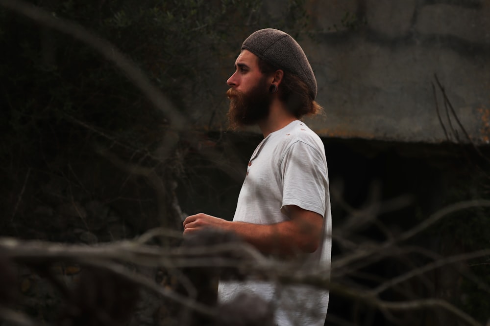 a man with a beard and a beanie walks through the woods