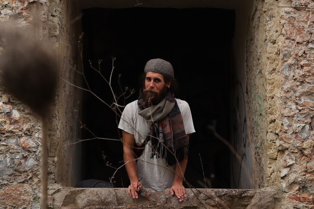 a man with a beard standing in a window