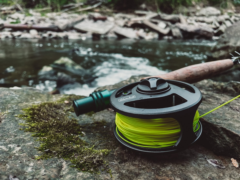 a reel and a spool of water sitting on a rock next to a river