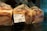 Several loaves of bread are wrapped in translucent plastic bags, each with a printed label showing nutritional information and the name 'Whole Milk Loaf'. The bread is organized on a reflective surface, and the packaging has a modern design with wavy lines.