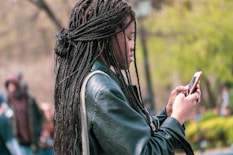 a woman with dreadlocks looking at her cell phone