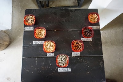 A diverse collection of seed varieties displayed in small glass jars with labels.