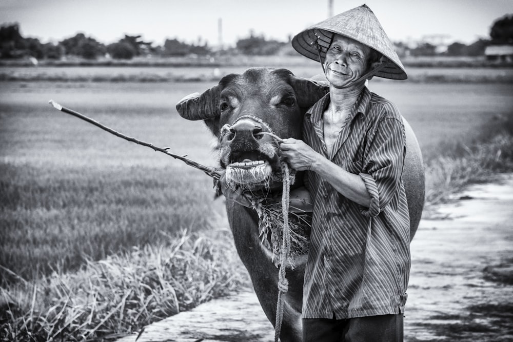 a black and white photo of a man holding a cow