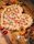 Close-up of a heart-shaped pizza with fresh basil and melted cheese on a rustic wooden table.