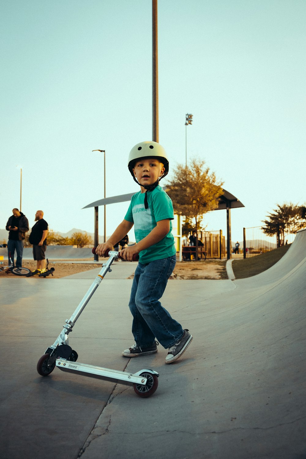 a young boy riding a scooter at a skate park