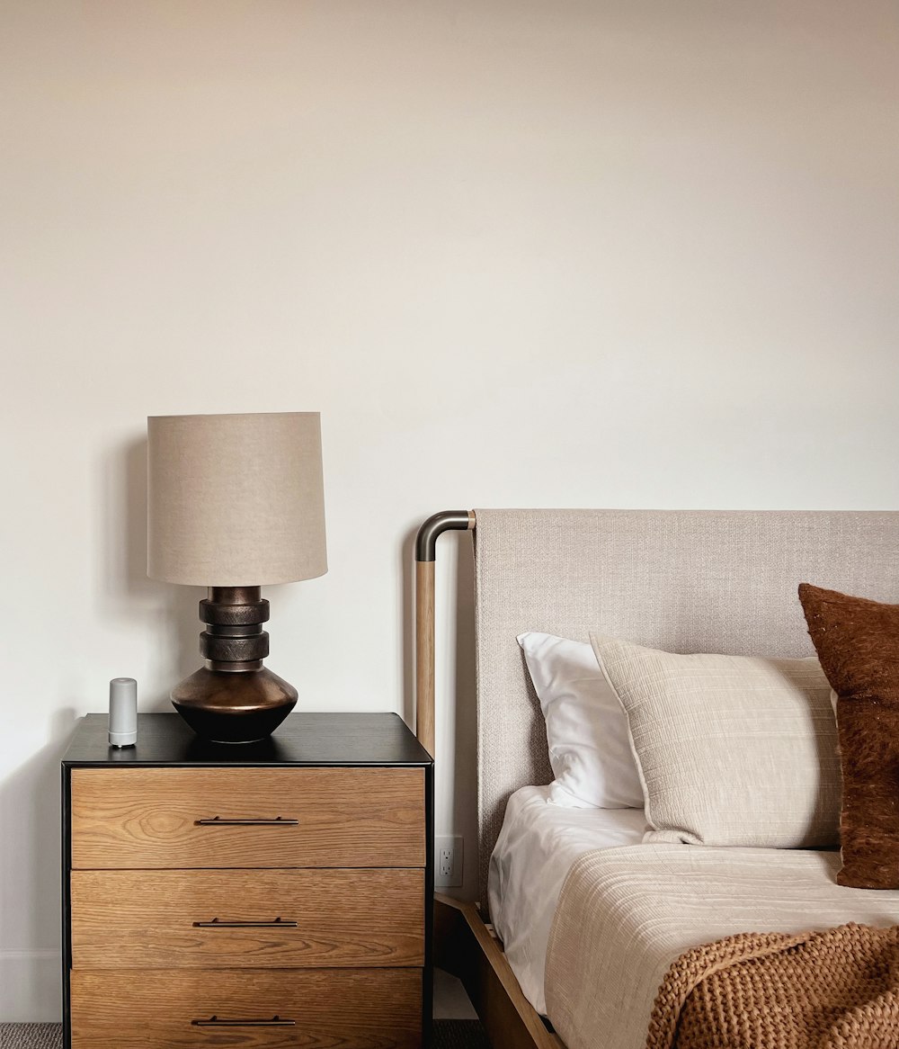 a bedroom with a bed and a nightstand with a lamp on top of it