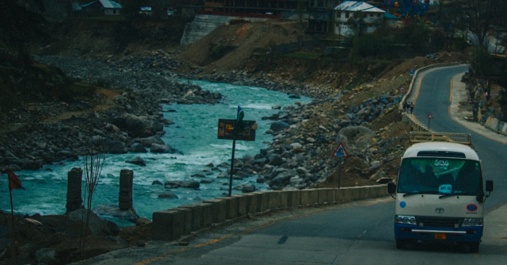 a bus driving down a road next to a river