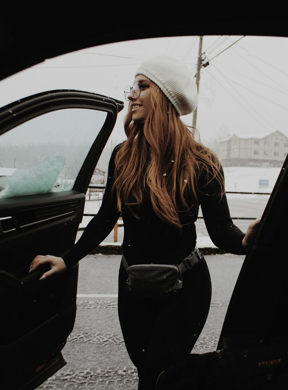 a woman with a hat and glasses is opening the door of a car