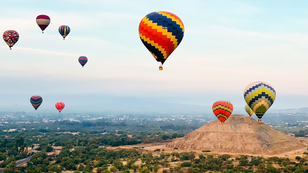 Eine Gruppe von Heißluftballons fliegt über einen Hügel