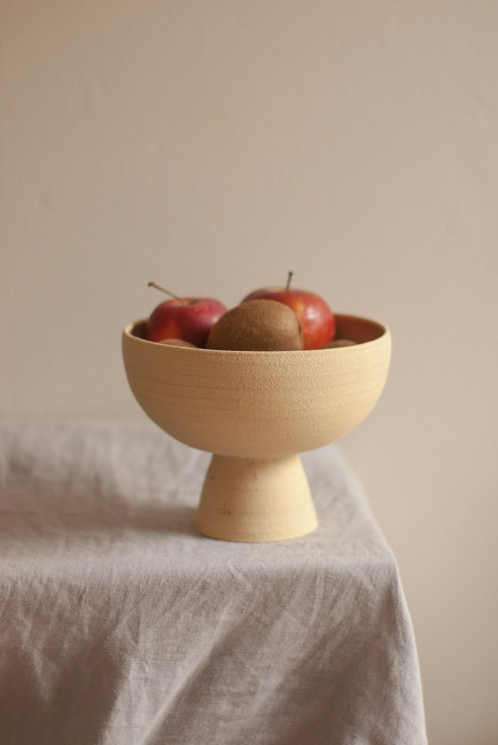 a wooden bowl filled with apples on top of a table