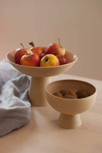 Brightly glazed ceramic bowls stacked with fresh fruit on a cozy kitchen table.