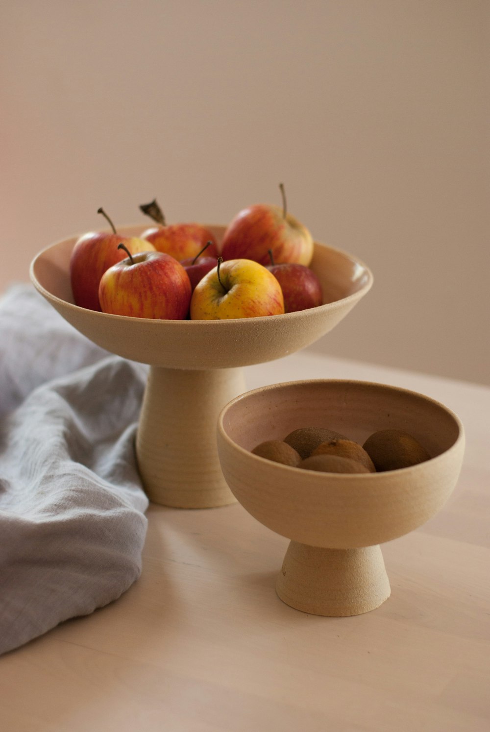 a bowl of apples sitting on a table next to a bowl of apples