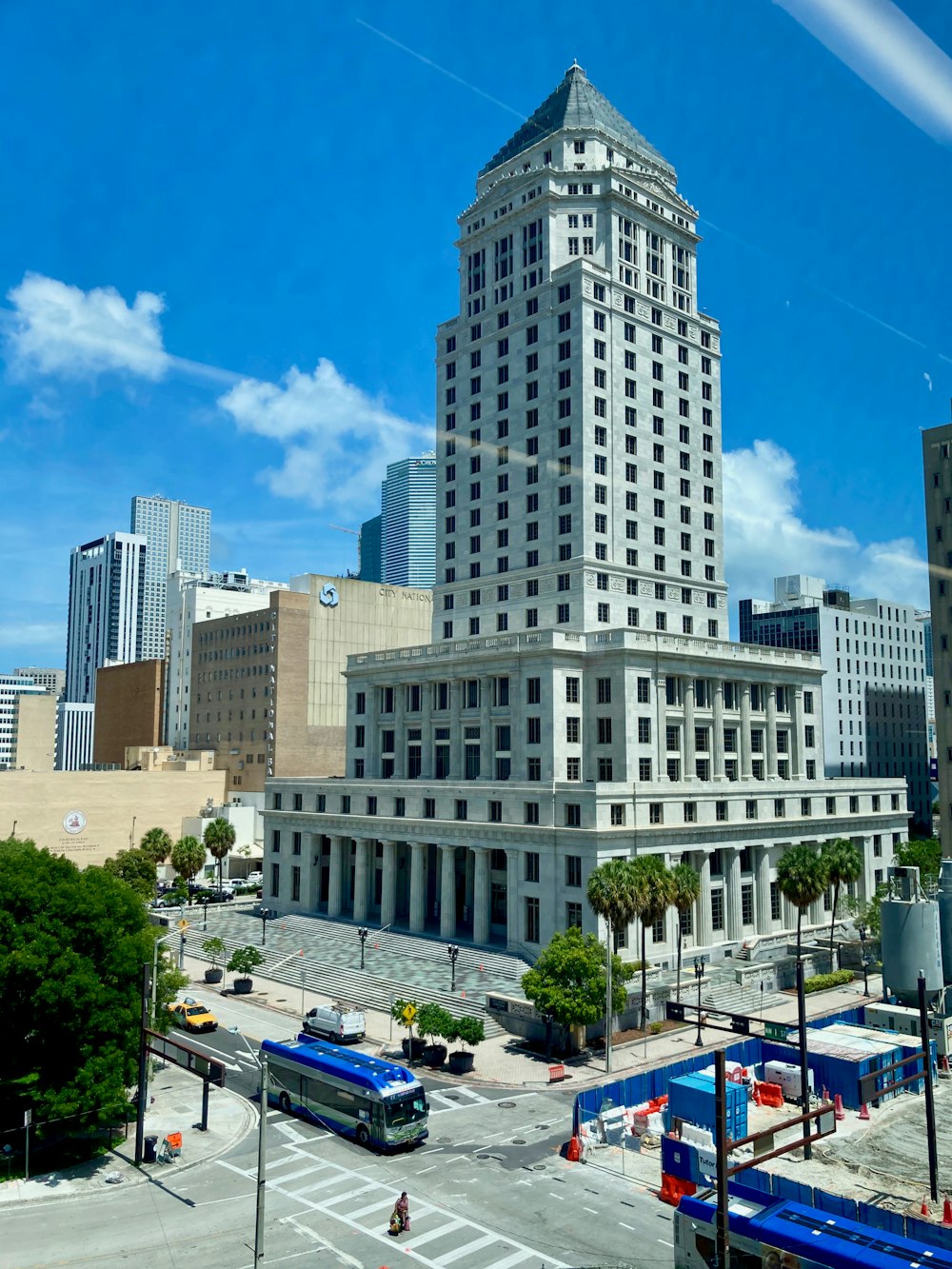 a large white building with a blue bus in front of it