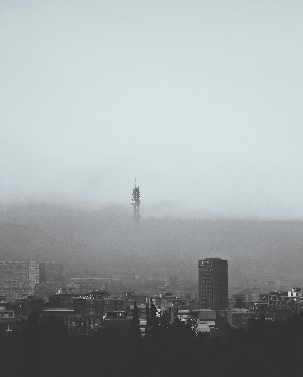 a black and white photo of a foggy city