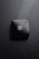 A black compact makeup case rests on a surface covered with water droplets. The compact case is sleek and has a logo with intertwined letters in the center, creating a sophisticated and luxurious impression.