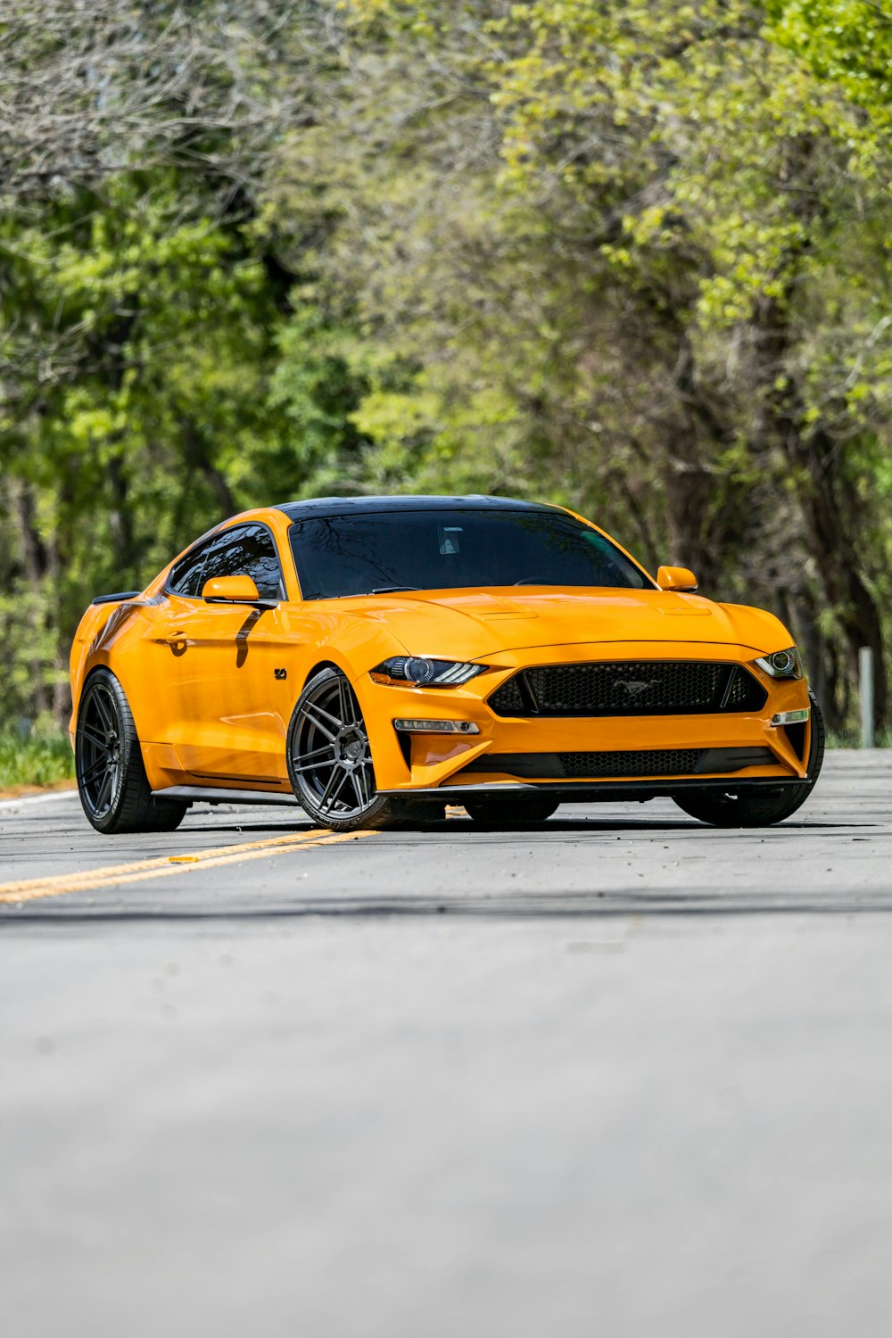 Un Ford Mustang amarillo estacionado al costado de la carretera