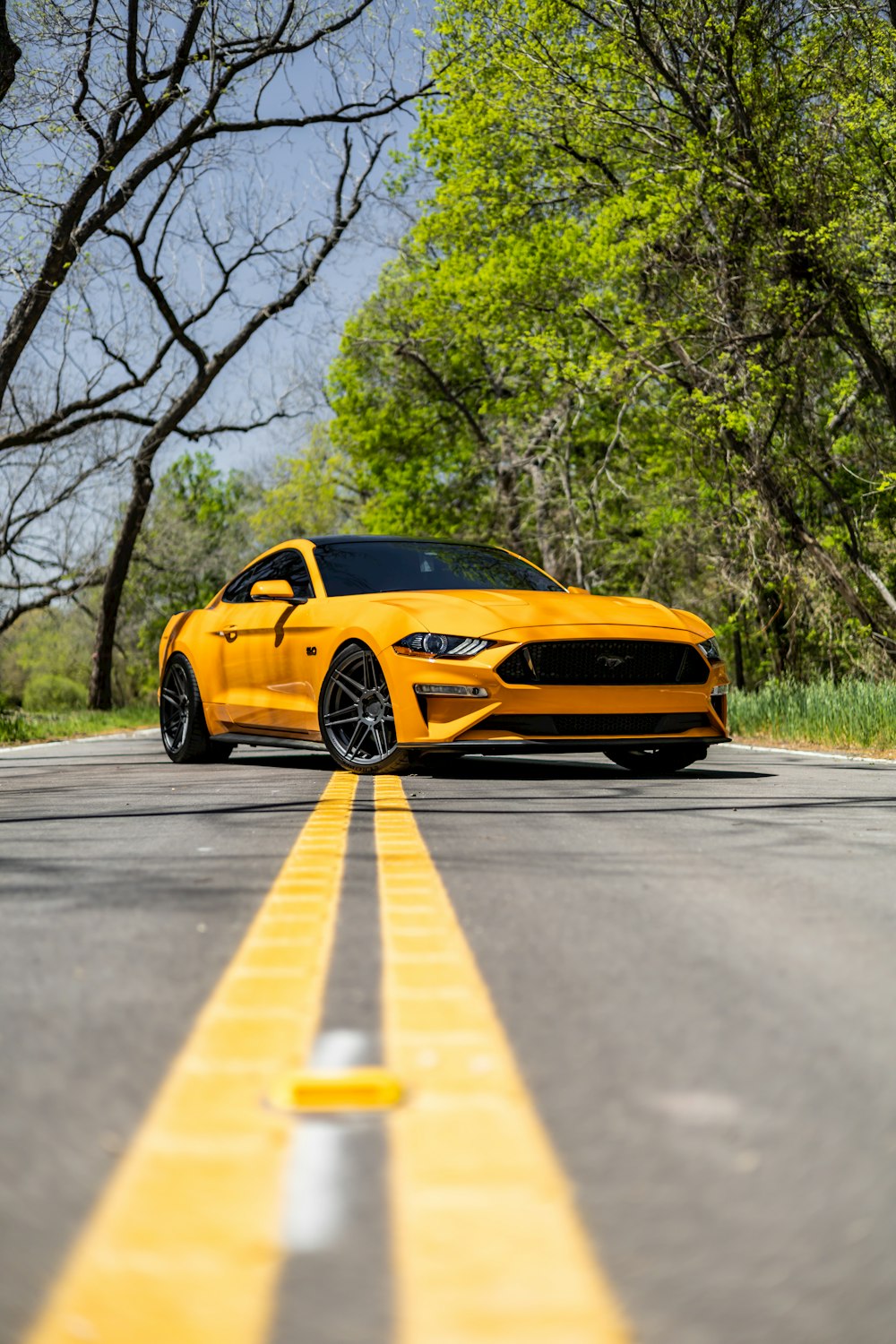 a yellow mustang parked on the side of the road
