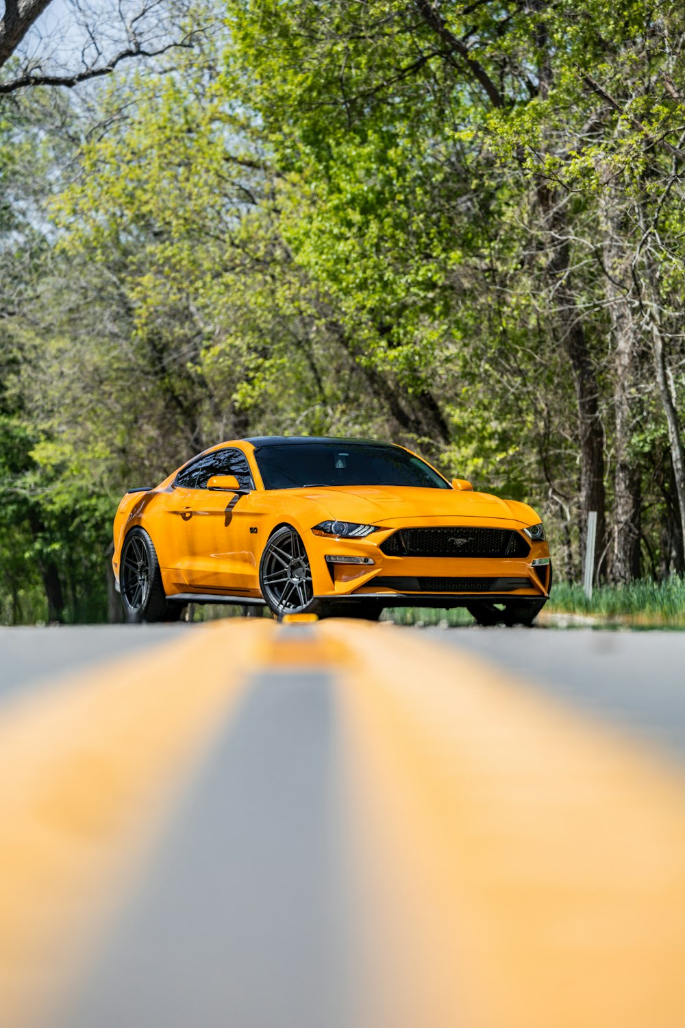 Un coche amarillo está conduciendo por la carretera