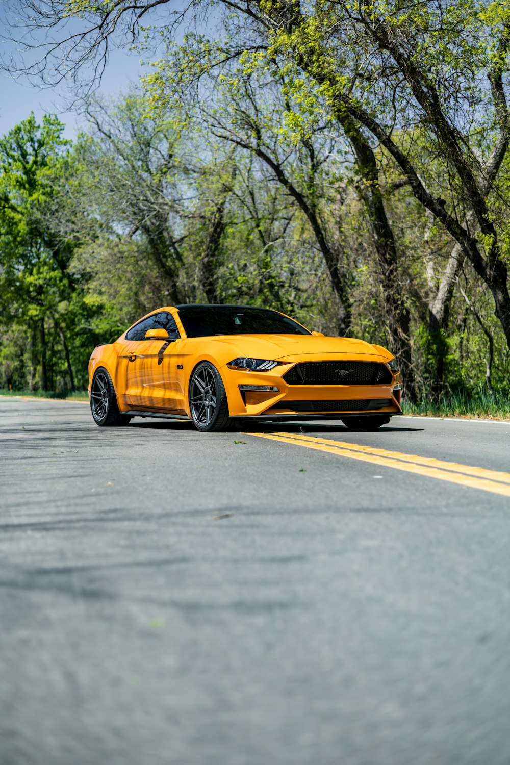 Un Ford Mustang amarillo estacionado al costado de la carretera