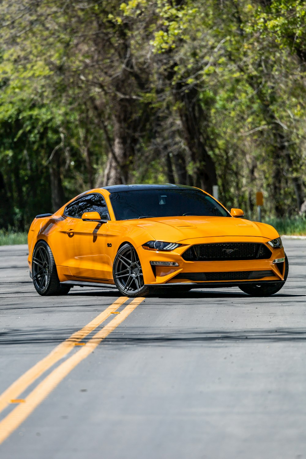 a yellow ford mustang parked on the side of the road