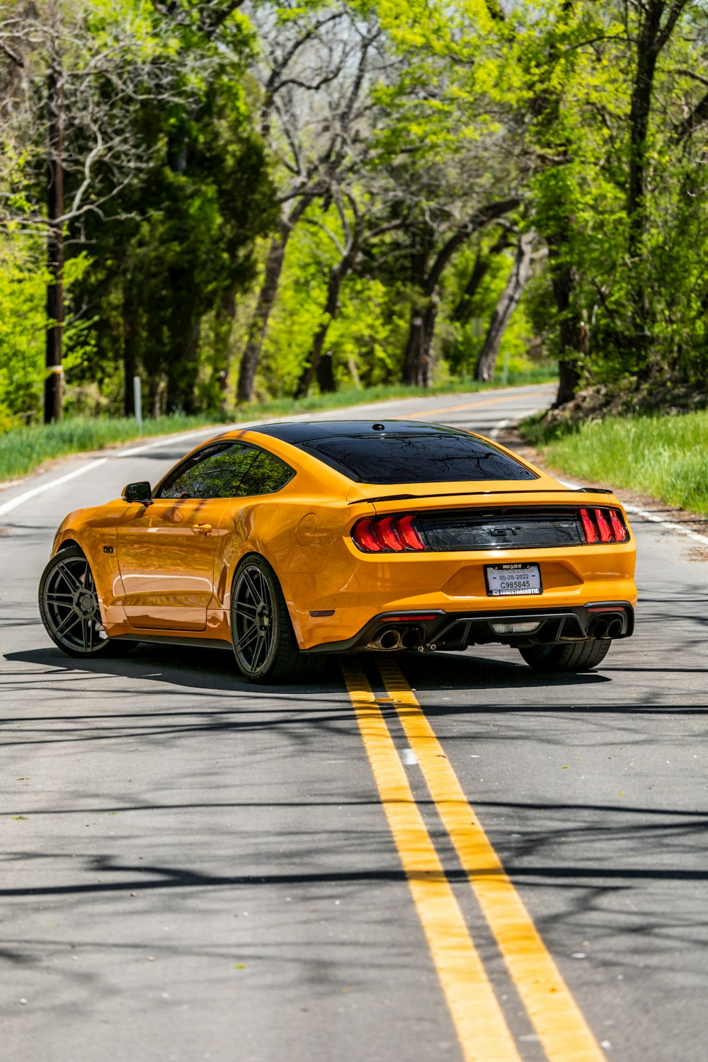 a yellow sports car driving down the road