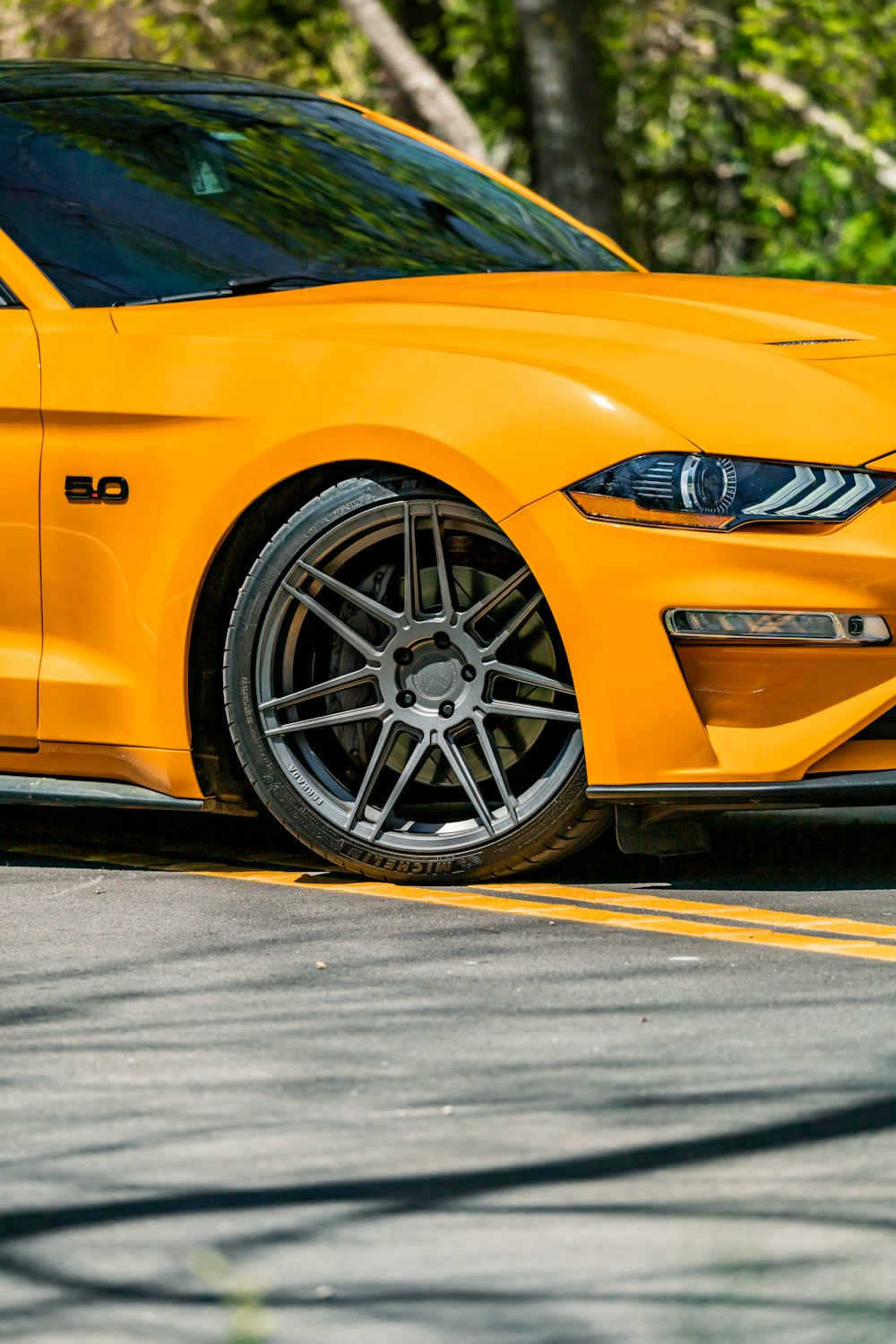 a yellow mustang parked on the side of the road