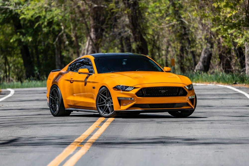 Un Ford Mustang amarillo conduciendo por la carretera