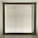 A large window with closed horizontal blinds, allowing minimal light through. The blinds have a neutral beige tone, and the window is set in a recessed wall, casting subtle shadows on the sill.