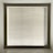 A large window with closed horizontal blinds, allowing minimal light through. The blinds have a neutral beige tone, and the window is set in a recessed wall, casting subtle shadows on the sill.