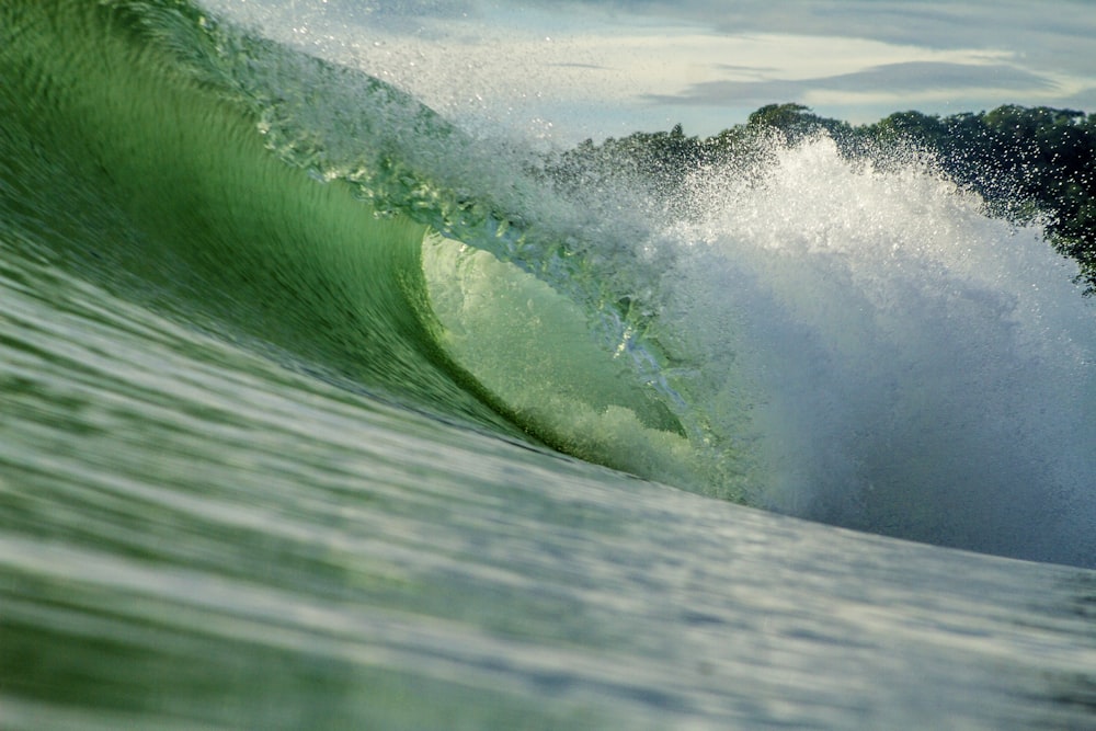 a large wave is breaking over a green surfboard