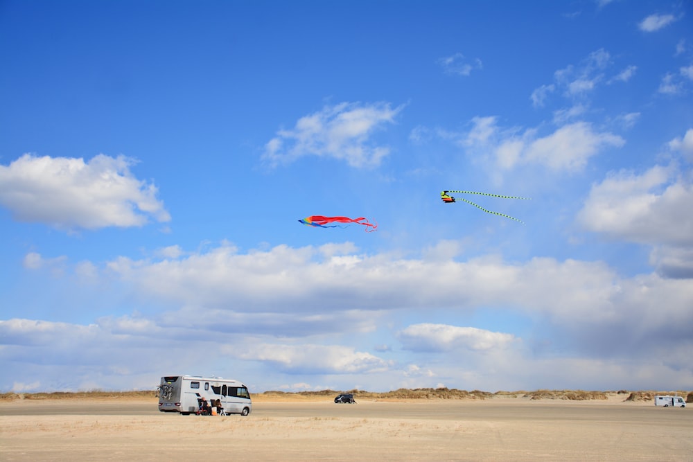 a couple of kites flying in the sky over a desert