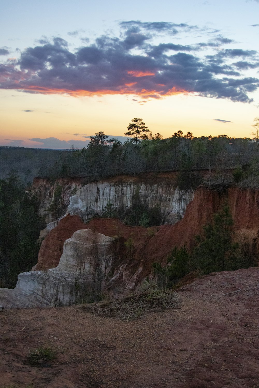 uma vista de um penhasco rochoso com um pôr do sol no fundo