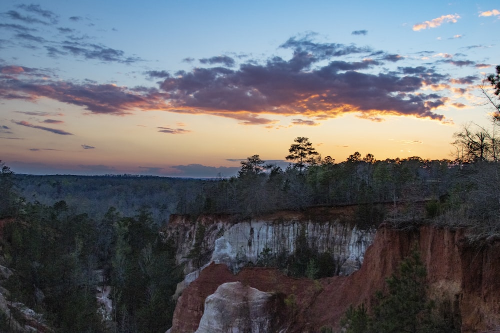 the sun is setting over a rocky cliff