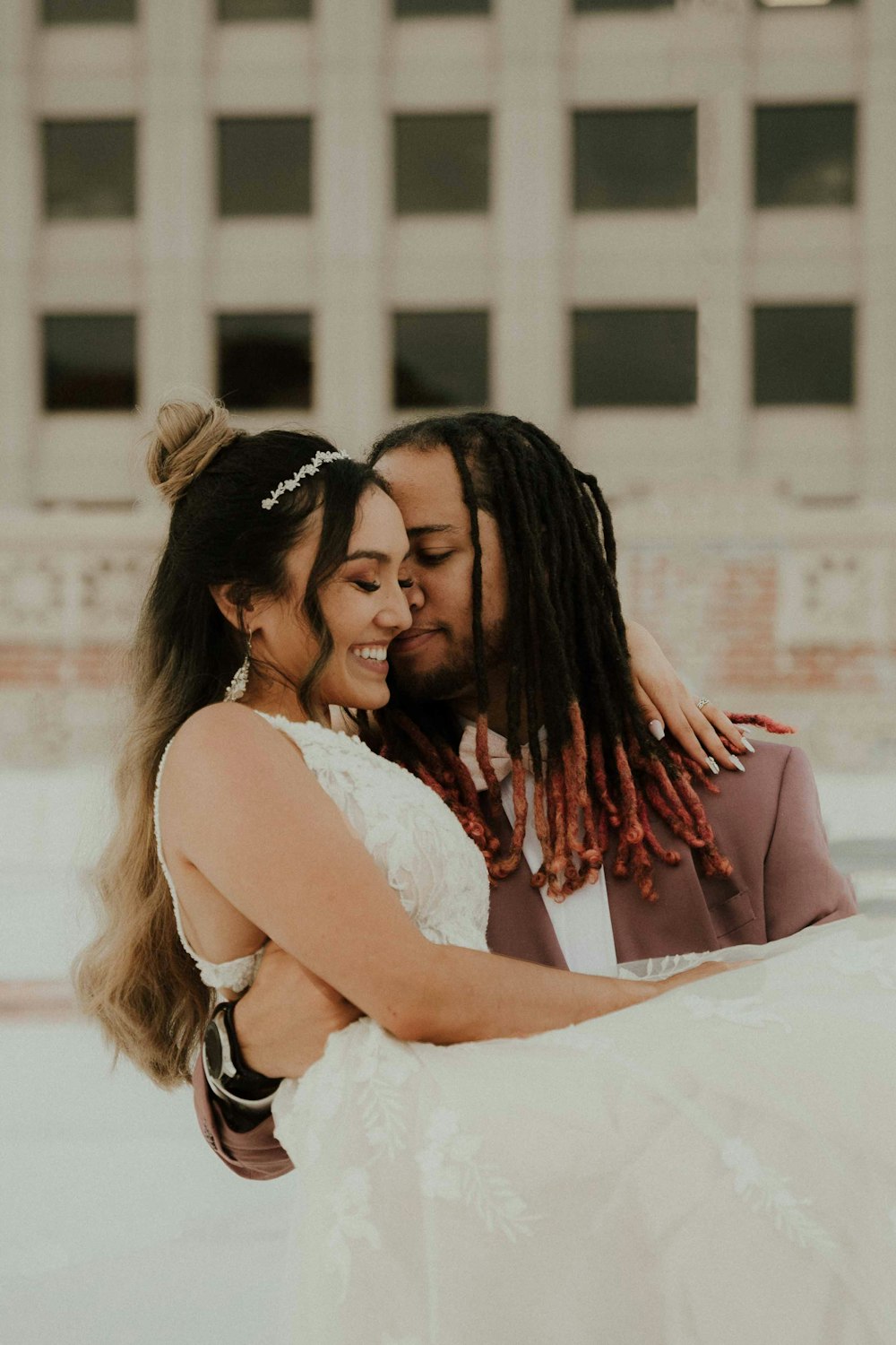 a man and woman hugging each other in front of a building