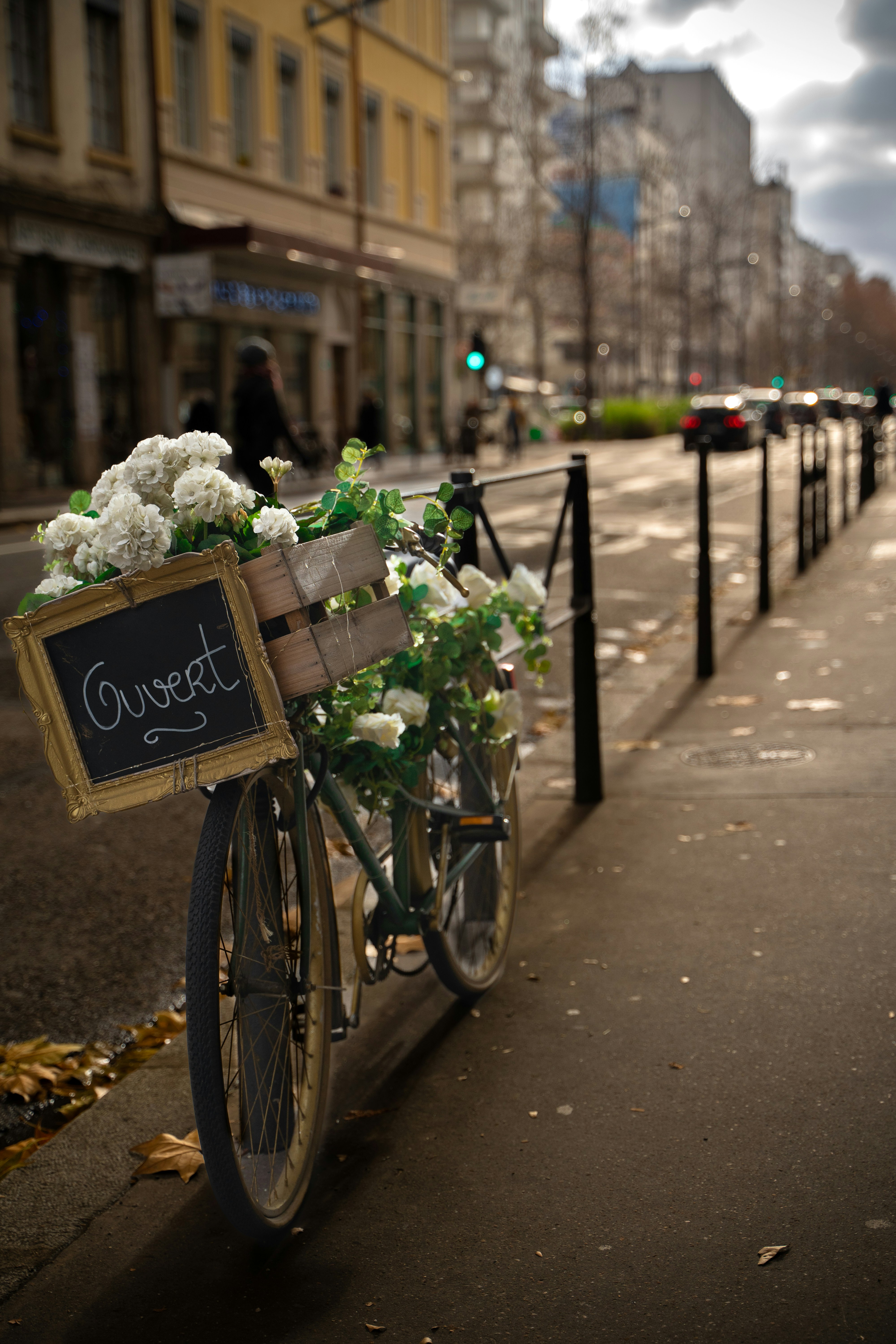 a bicycle with a basket full of flowers parked on the side of the street