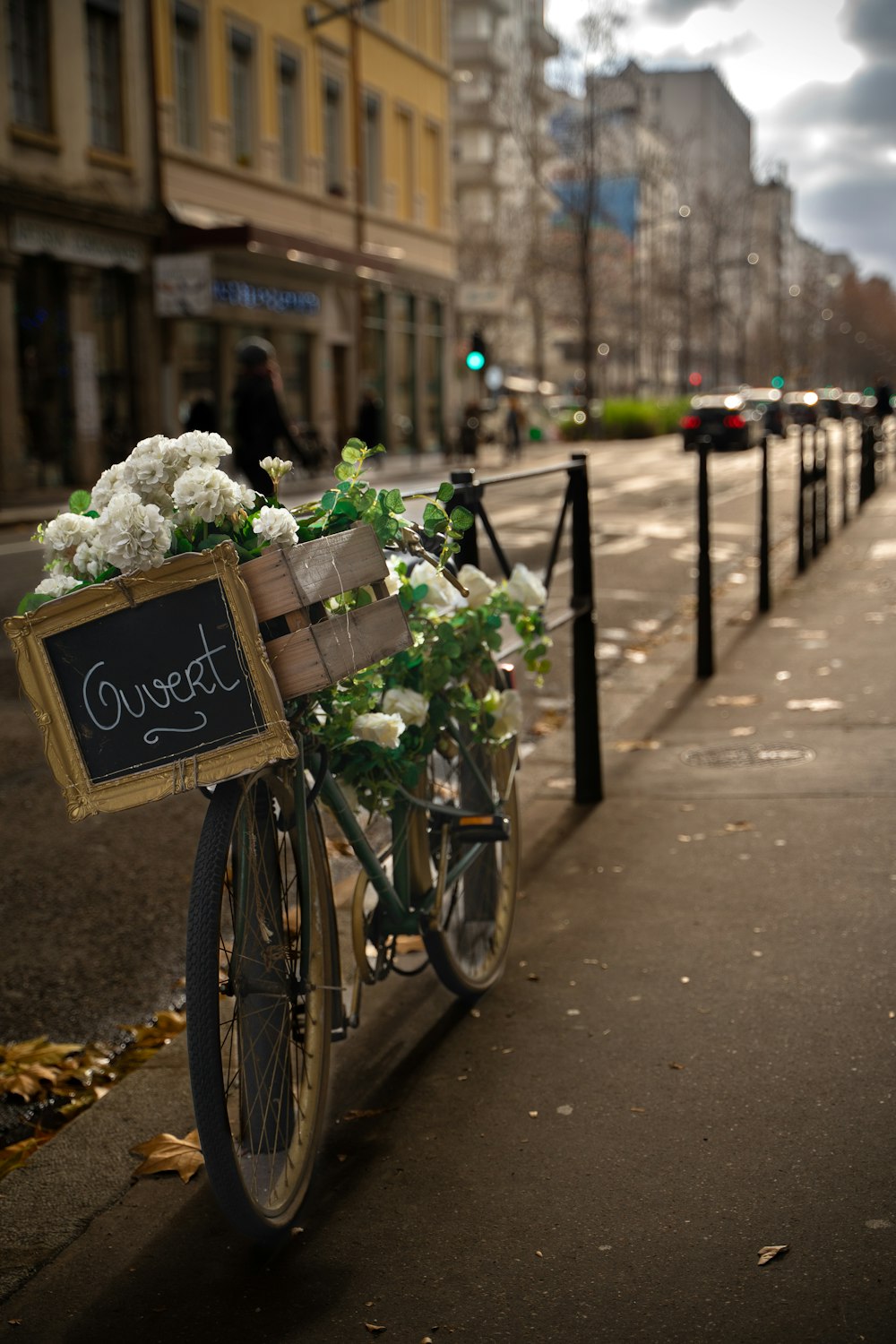 a bicycle with a basket full of flowers parked on the side of the street