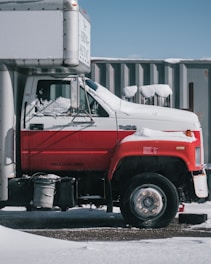 a red and white truck parked in front of a building