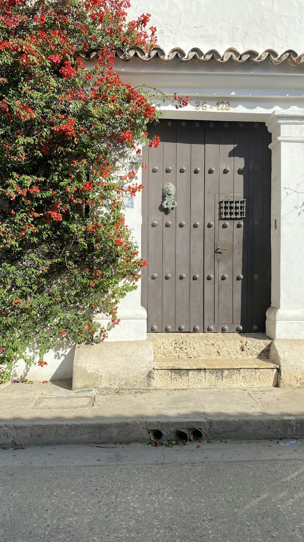 a white building with a black door and red flowers