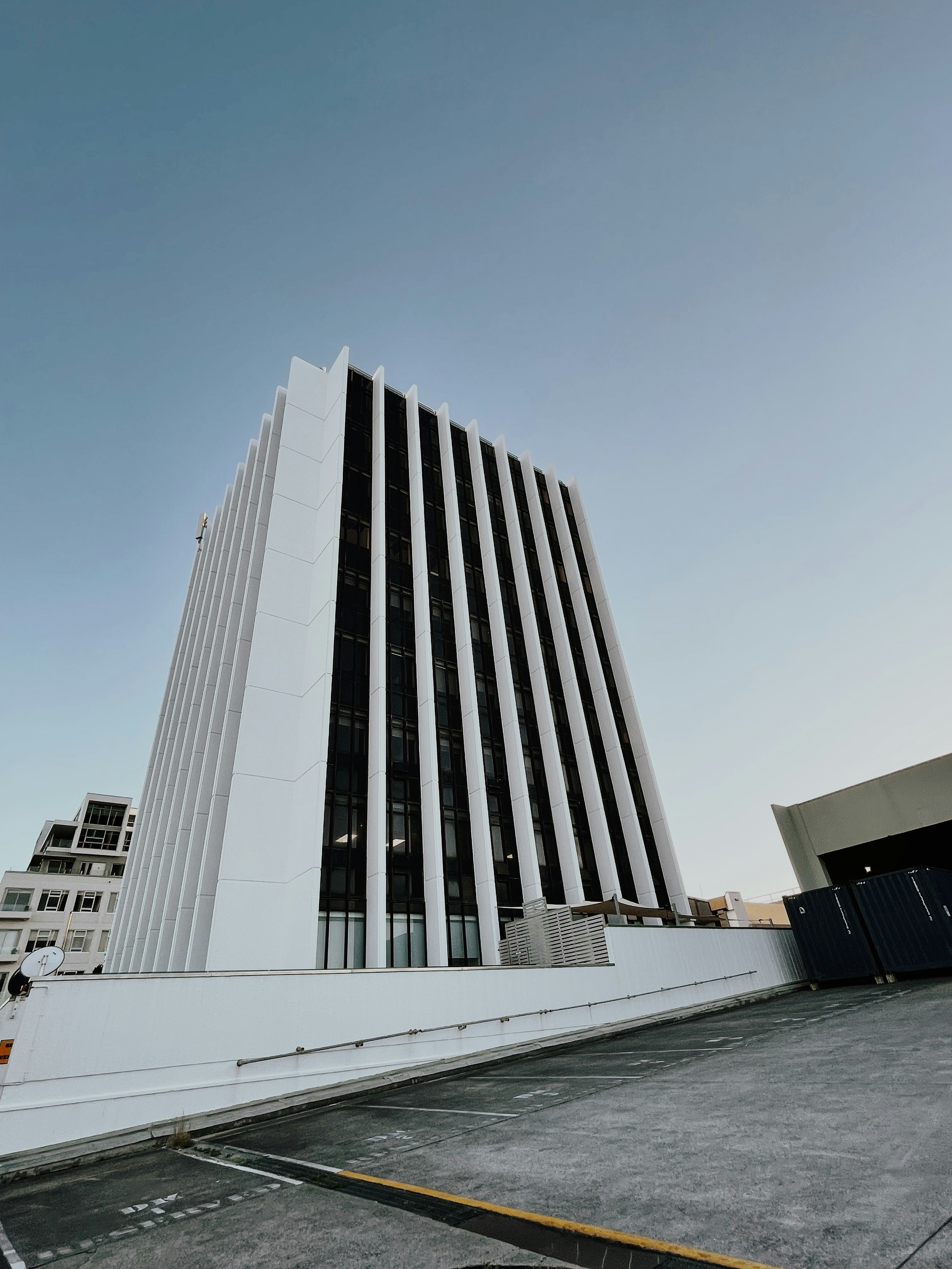 a tall white building sitting next to a parking lot