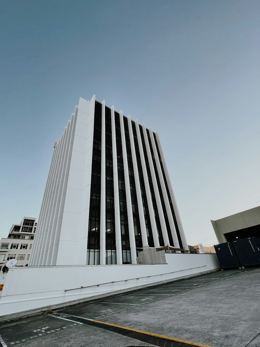 a tall white building sitting next to a parking lot