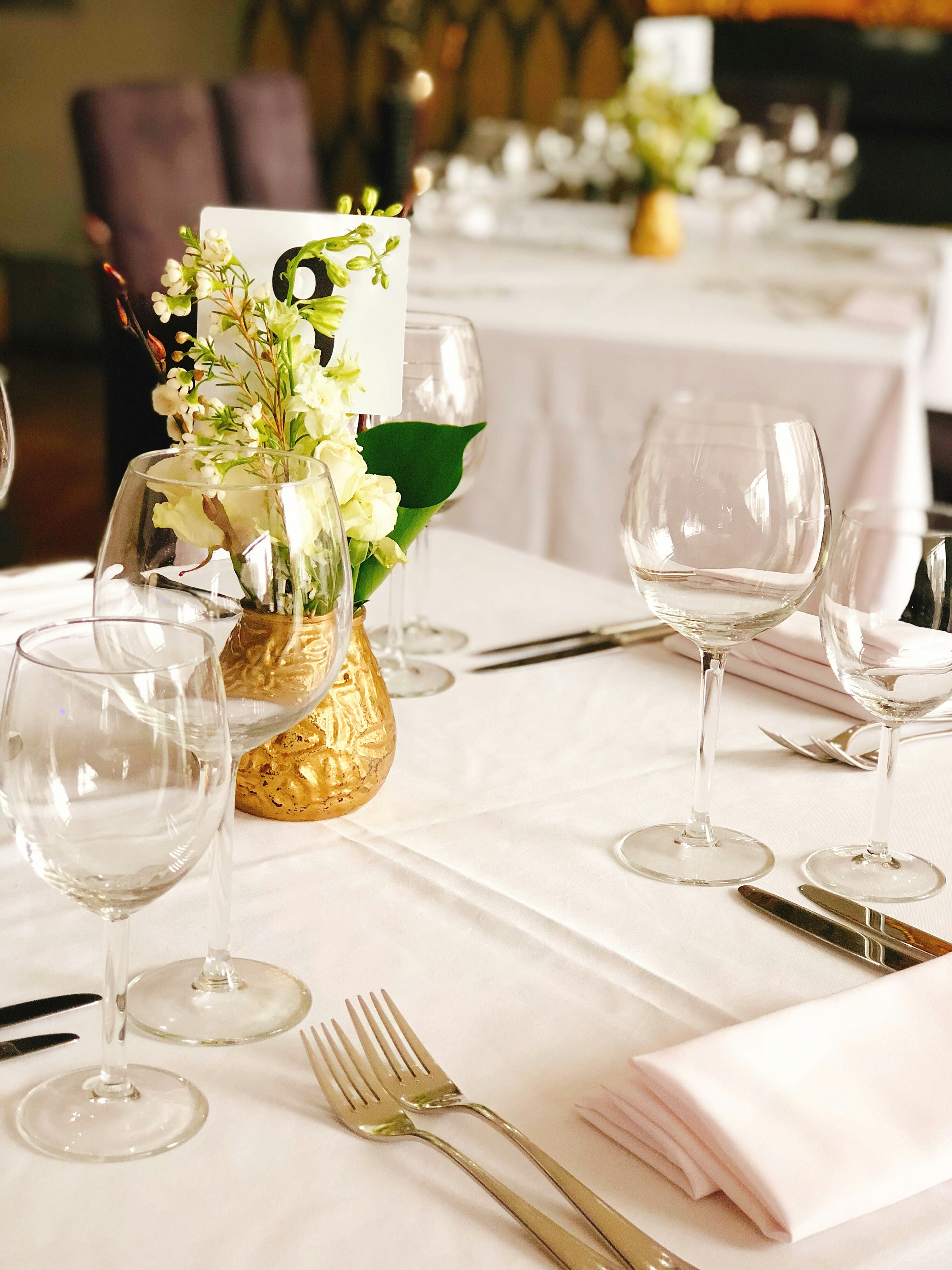 Floral centerpiece arrangement with roses and greenery on white tablecloth at event